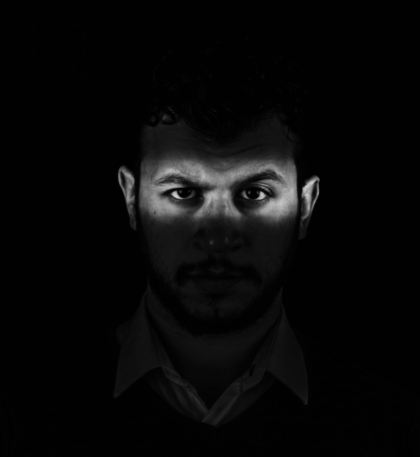 Man in dark shadow showing eyes.